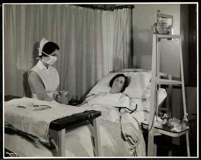 Eine maskierte Krankenschwester mit einem Patienten in einem Raum im Sloane Medical Hospital, Broadway und 168th Street, New York, 1932 von Byron Company